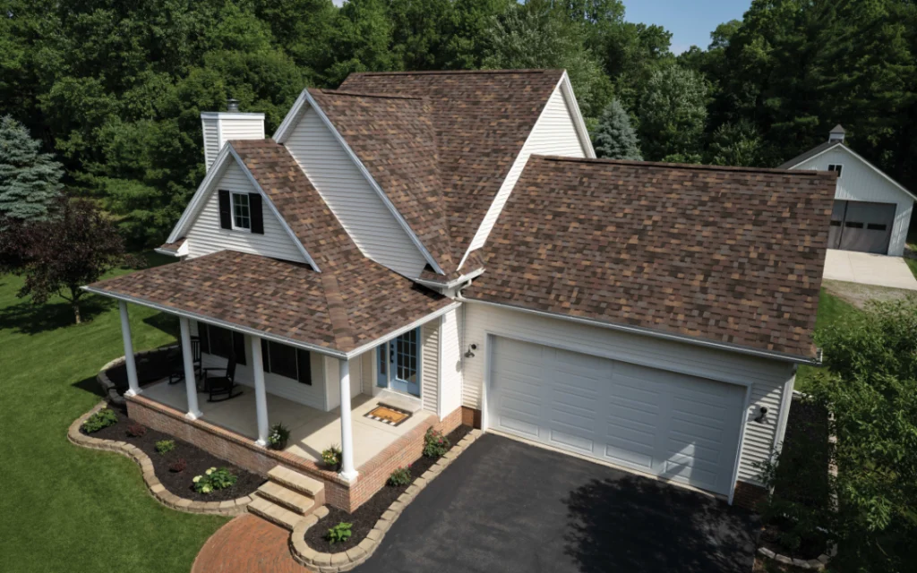 Brown shingle roof on a white home with a front porch and garage