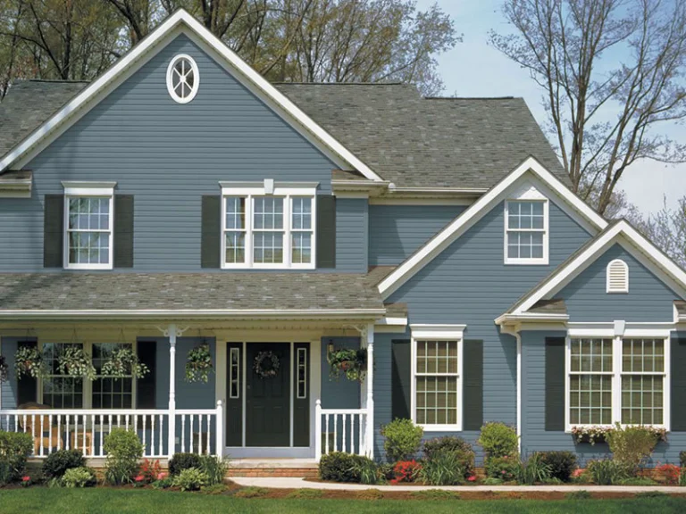 Blue-gray siding colonial with dark shutters and a front porch
