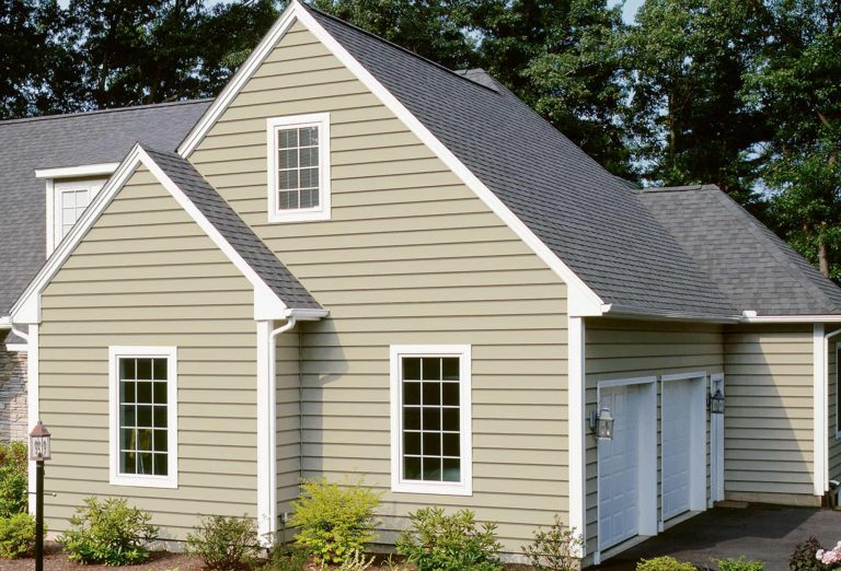 Cape-style home with tan siding, white trim and a gray shingle roof