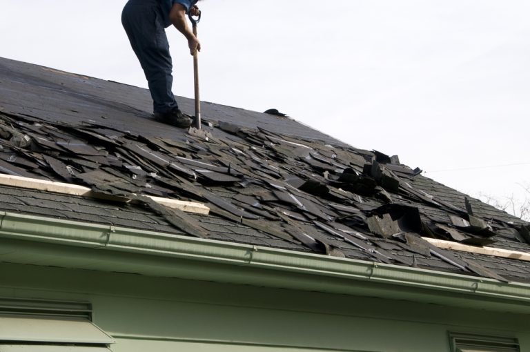 Roofer tearing off old shingles during a roof replacement