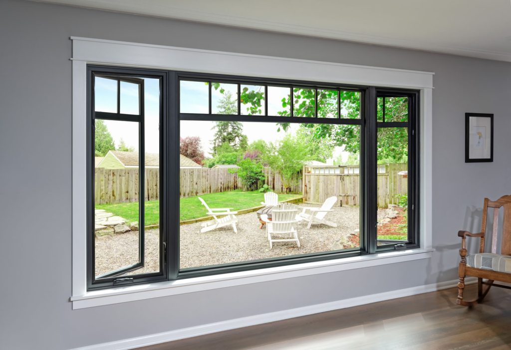 Large black-framed casement window looking out on a backyard
