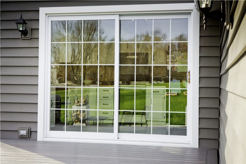 New white sliding patio door with grids in gray siding