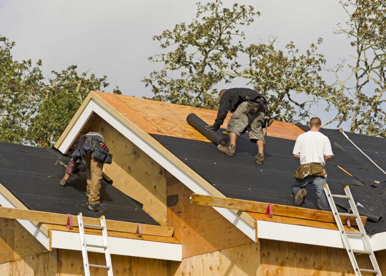 Roofers installing new shingles over fresh roof decking