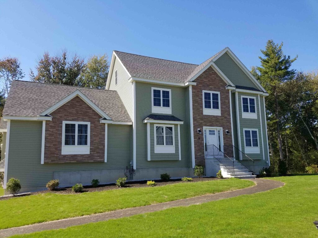 Two-story home with stacked stone and sage green siding