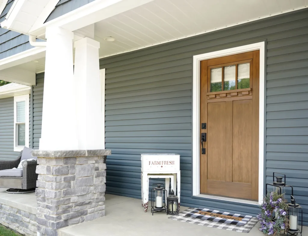 Navy blue siding with a stone column and wood front door