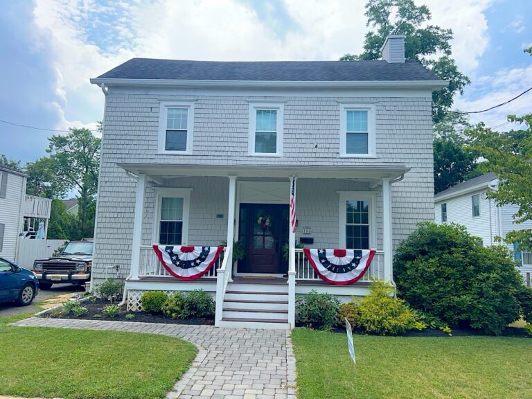 Colonial with new white shake-style siding and a front porch in Red Bank, NJ